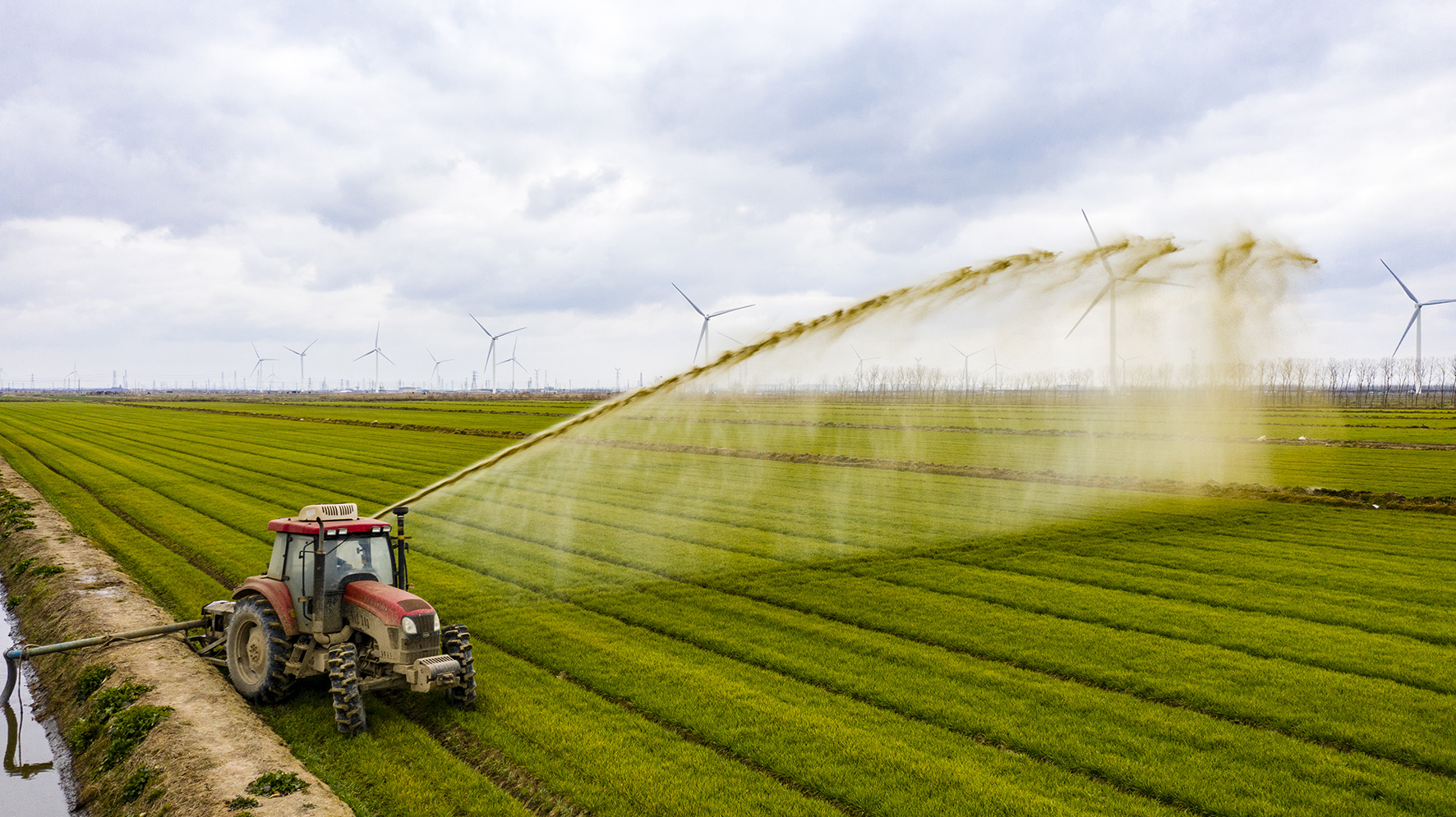上图为农户正在为小麦喷洒沼液有机肥.